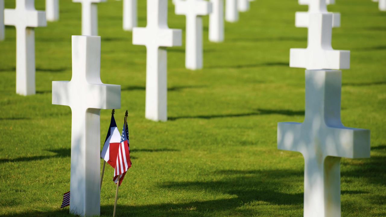 cemetery with white crosses and american flags